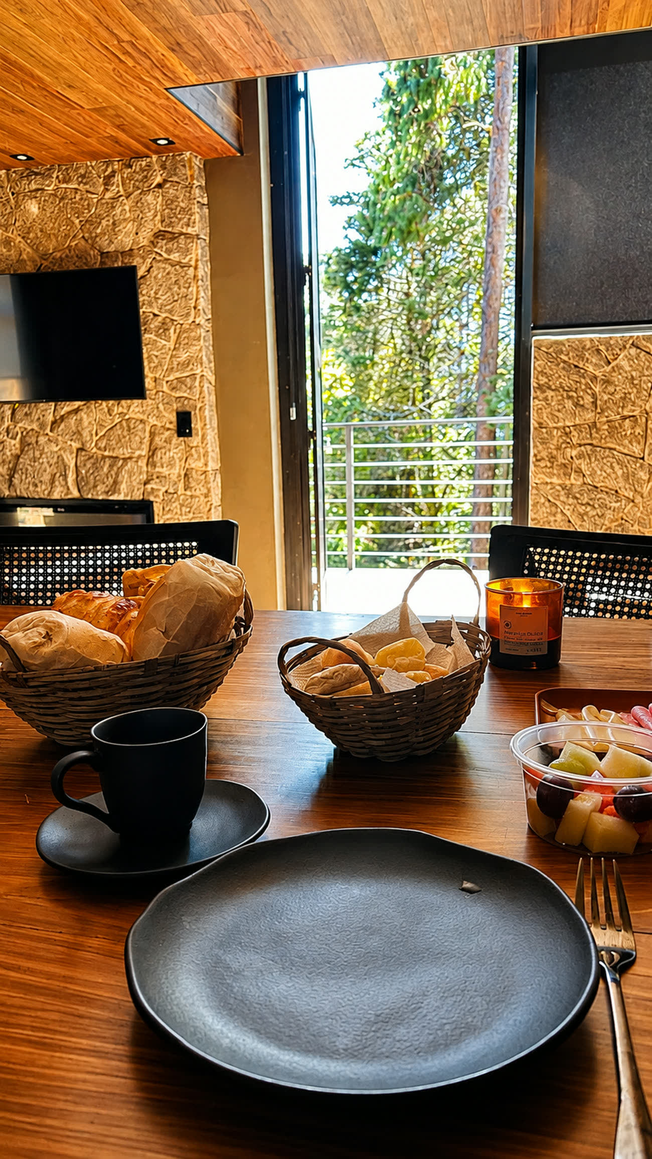 Cesta de pães e frutas sobre a mesa, com a porta aberta para o deck
