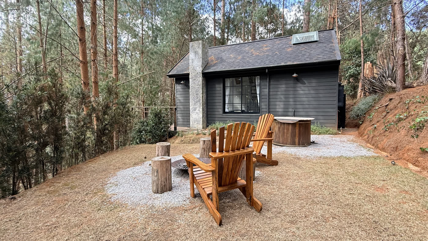A área externa da Farm House de dia, com as cadeiras de madeira, o firepit e o ofurô