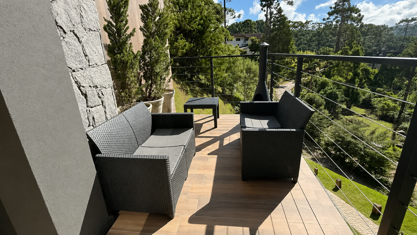 O deck externo com poltronas e a vista aberta para o vale